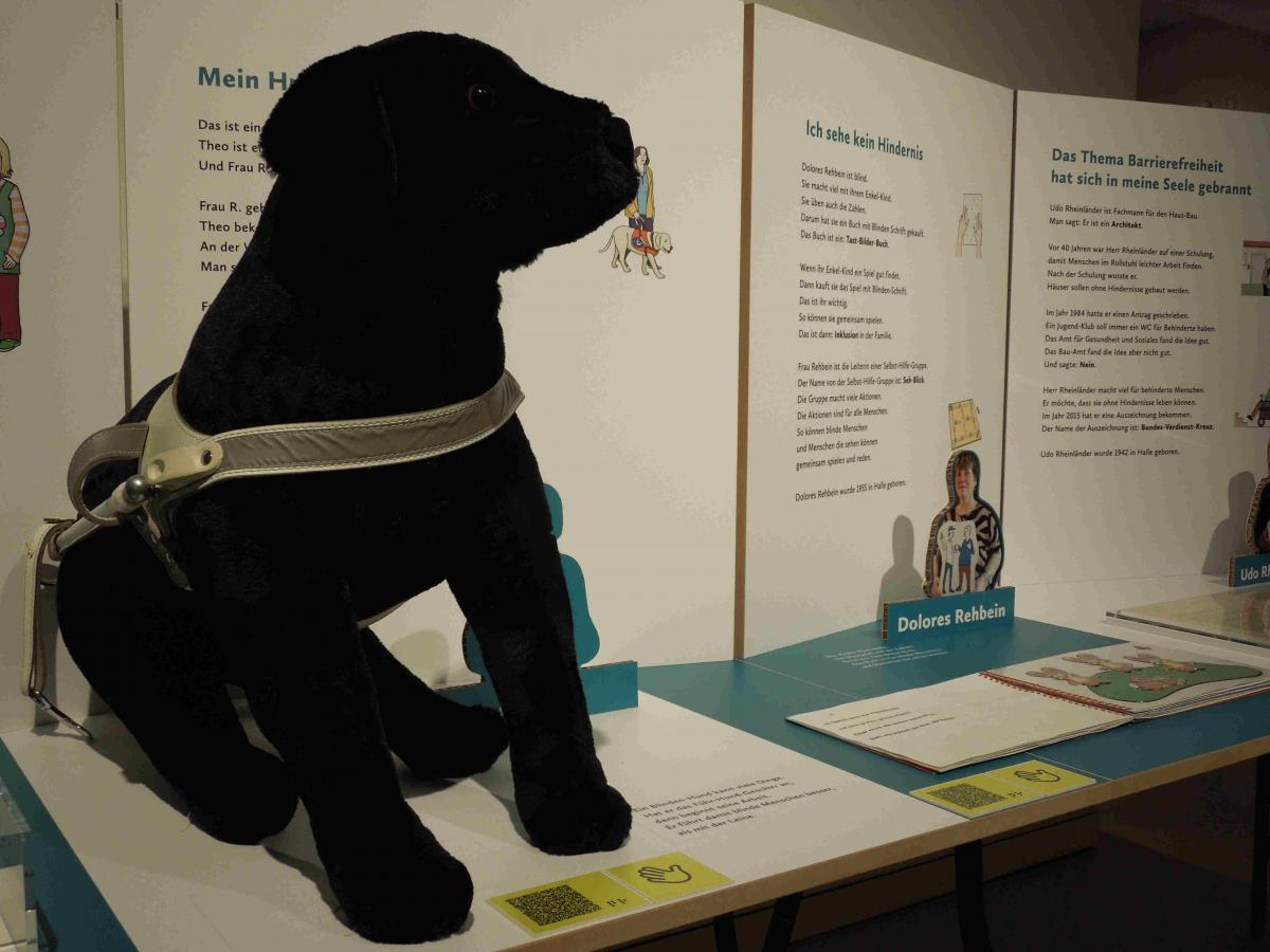 Ausstellungstisch mit lebensgroßem Plüschhund mit Führhundgeschirr