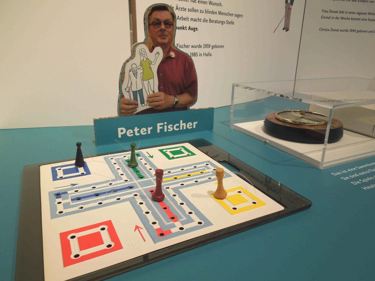 Ausstellungstisch mit Spielbrett, Barometer und Foto von Peter Fischer