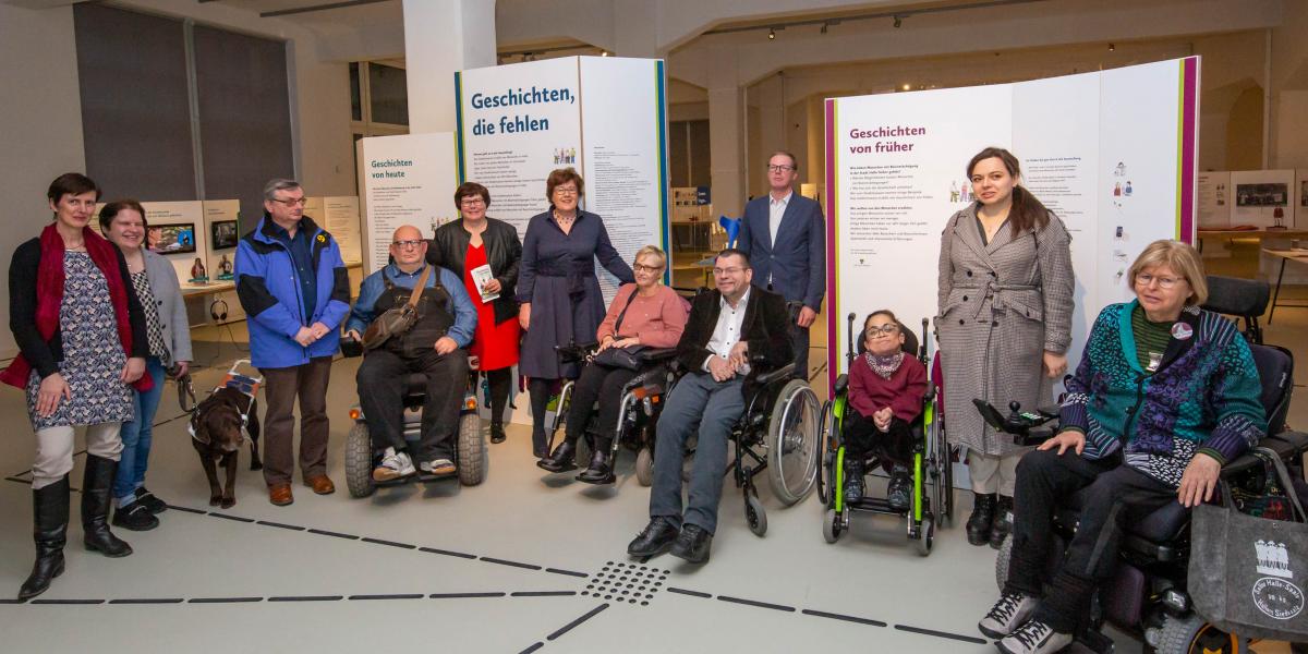 Gruppenbild mit 12 Menschen in der Ausstellung, darunter Ausstellungsbeteiligte, Petra Grimm-Benne und Marcus Graubner