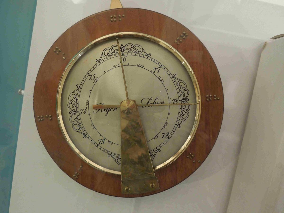 Rundes Wand-Barometer auf hölzerner Grundplatte mit Ziffernblatt aus Metall und Zeigern aus Messing.
