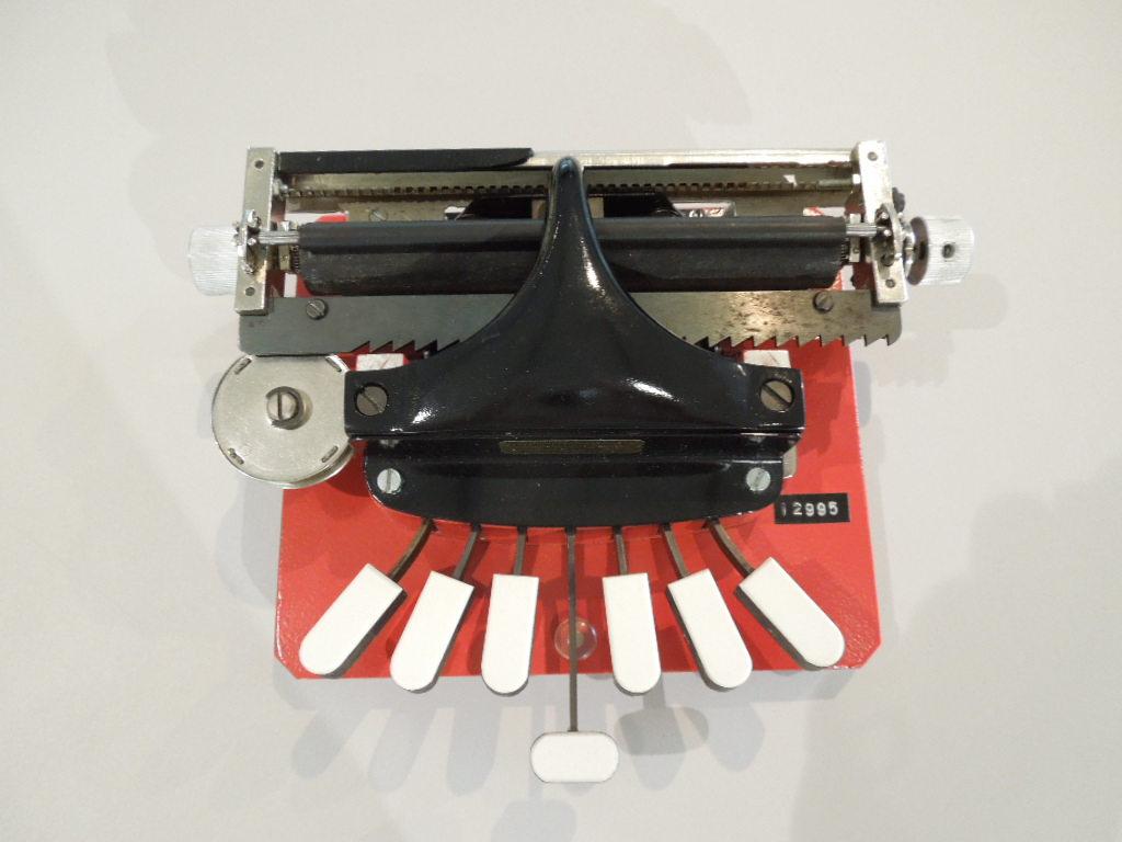 Feminin anmutende Punktschriftmaschine in Rot-Schwarz-Weiß